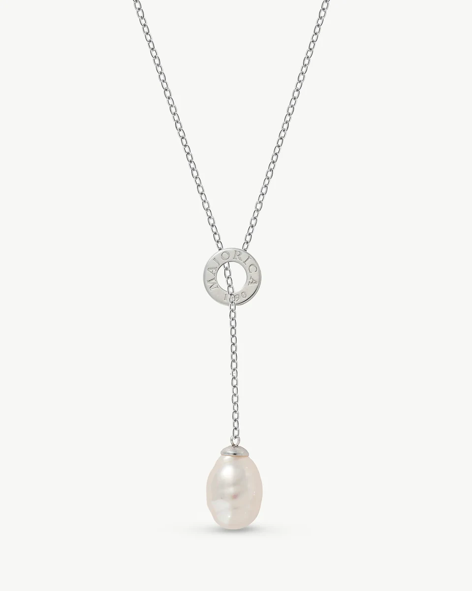 Collier avec perle baroque blanche, vue de face sur fond blanc, détail de l'anneau métallique gravé.