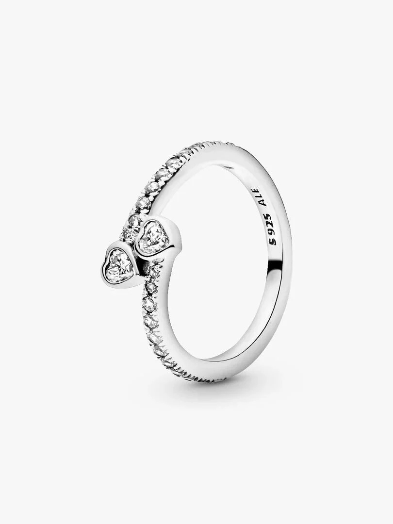Silver ring with two intertwined heart shapes and cubic zirconia, side angle view on white background.