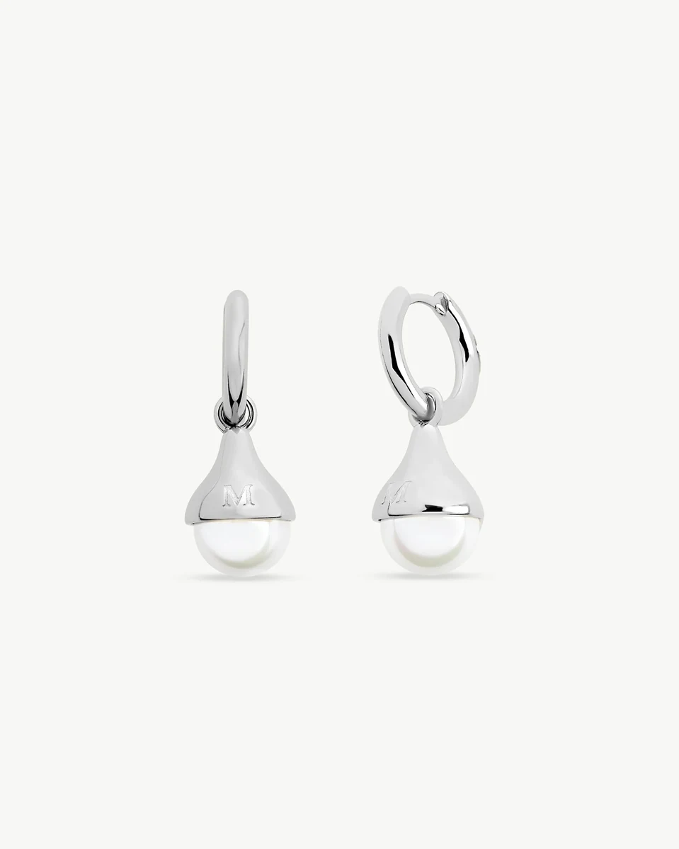 Paire de boucles d'oreilles créoles avec perle, vue de face sur fond blanc, détail du gravage argenté.