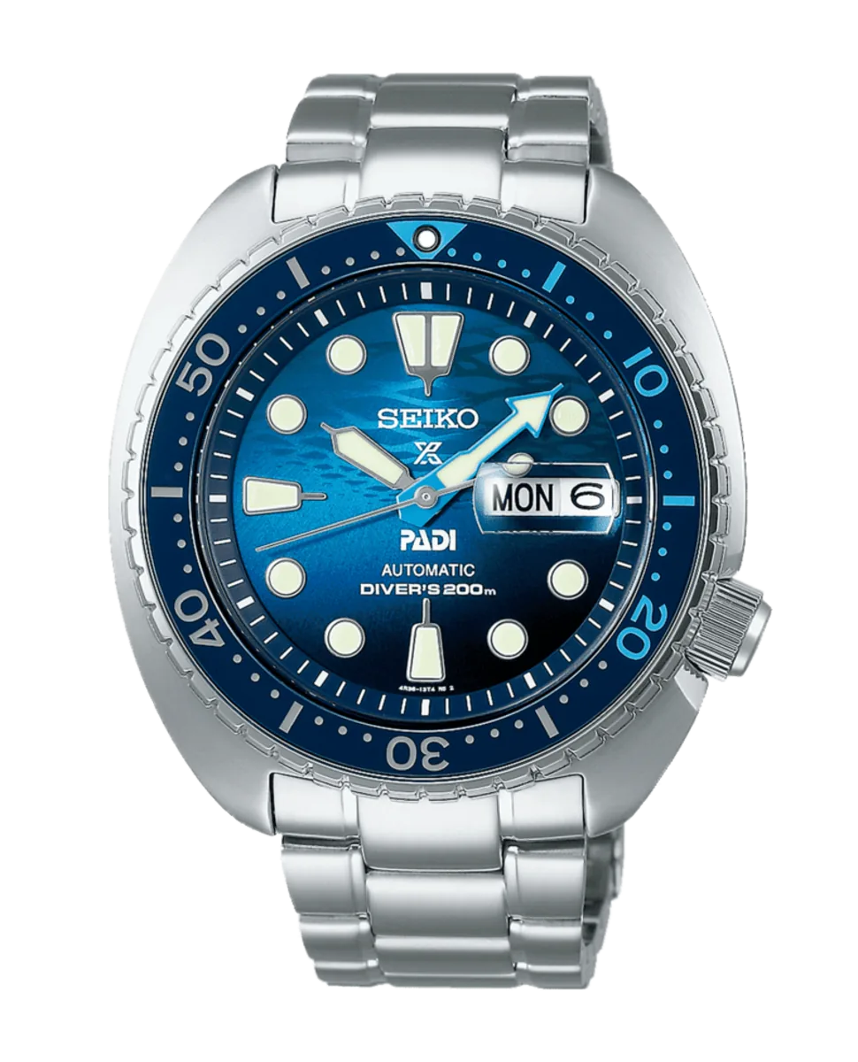 Vista frontal del reloj, esfera azul con bisel rotatorio y brazalete de acero, fondo blanco.