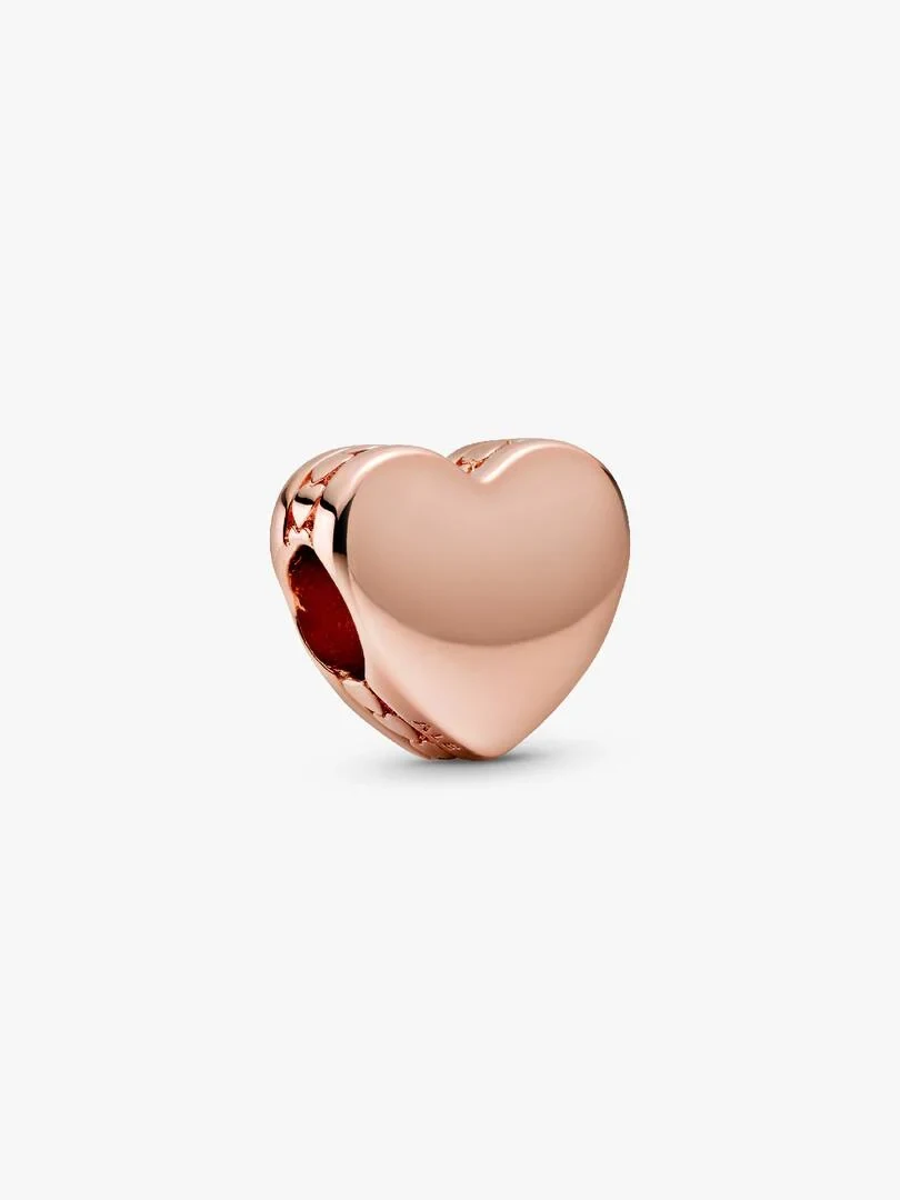 Charm de corazón en oro rosa visto en ángulo tres cuartos, fondo blanco neutro.