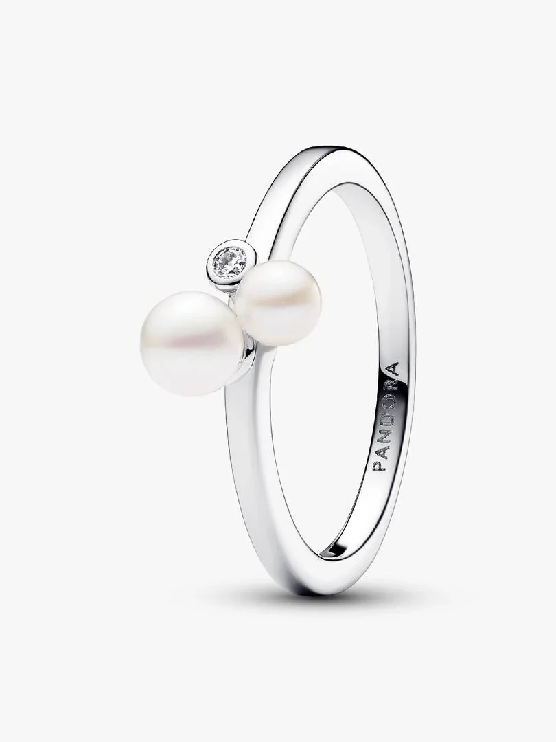 Silver ring with two pearls and a cubic zirconia, side angle view on white background.