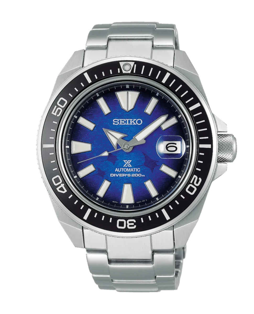 Vista frontal del reloj, esfera azul con motivo texturizado, bisel rotatorio negro y brazalete de acero, fondo blanco.