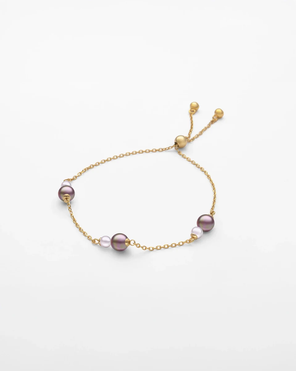 Goldene Gliederkette mit Auberginen- und Rosé-Perlen, Draufsicht auf weißem Hintergrund.