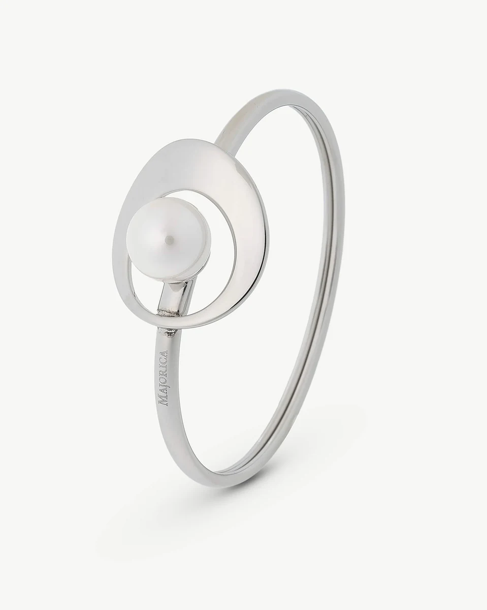 Bracelet en acier avec perle blanche centrale, vue de trois quarts sur fond blanc.