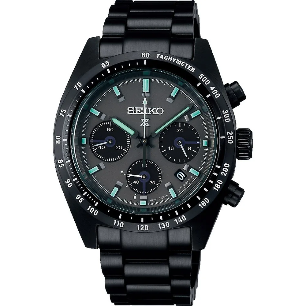 Vista frontal del reloj con esfera negra y bisel taquimétrico, centrado sobre fondo blanco.
