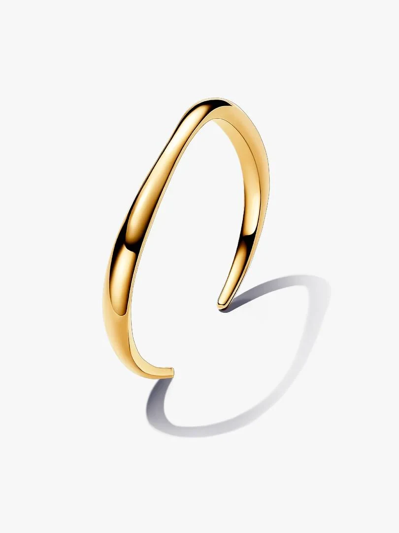 Bracelet jonc doré au profil ondulé, vue de profil inclinée sur fond blanc avec ombre douce.