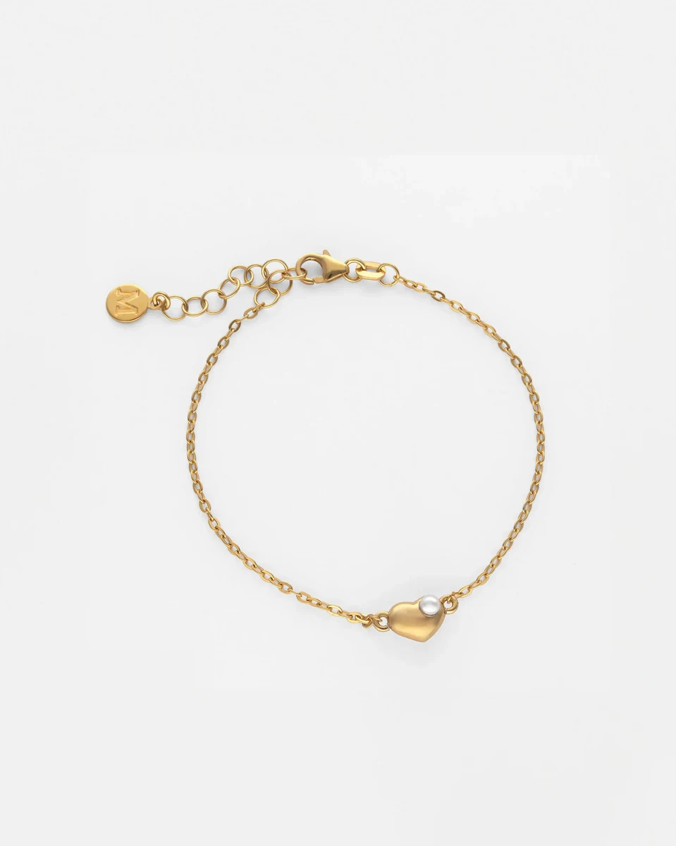 Draufsicht auf das Armband mit Herzanhänger und Perle auf weißem Hintergrund, inklusive Karabischließe.