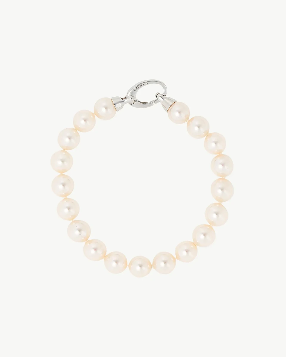 White pearl bracelet arranged in a circle on a white background, top view showing the silver clasp detail.