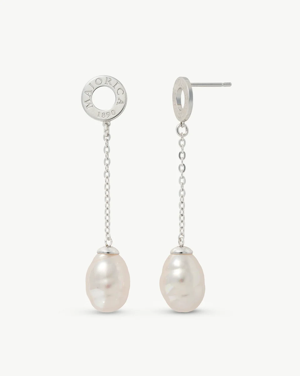 Vista frontal y lateral de los pendientes largos, fondo blanco, detalle del cierre de pincho y la perla barroca.