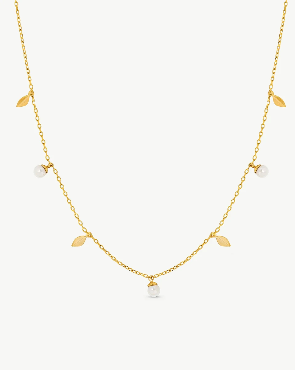 Collier doré avec feuilles et perles blanches sur fond blanc, vue frontale complète.