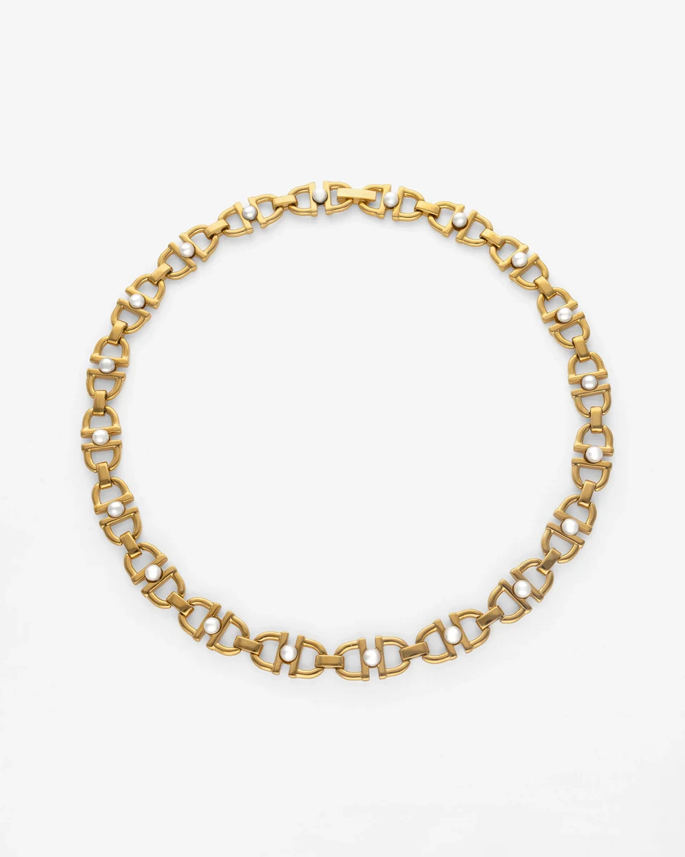 Goldene Gliederkette mit weißen Perlen, kreisförmig auf weißem Hintergrund angeordnet, Draufsicht.