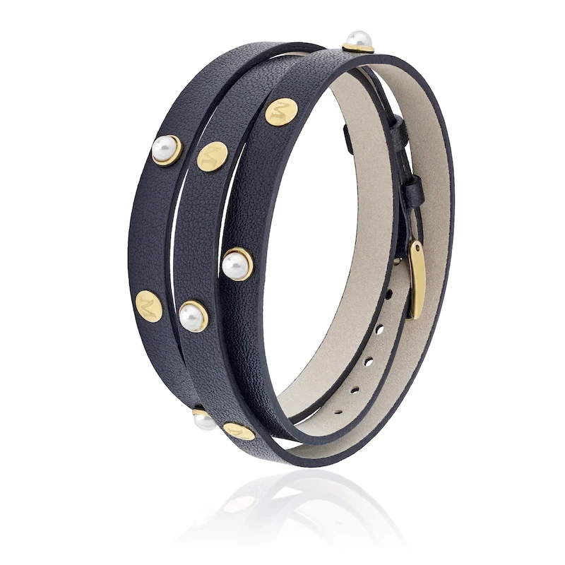 Schwarzes Lederarmband mit weißen Perlen und Goldakzenten, schräge Ansicht auf weißem Hintergrund.