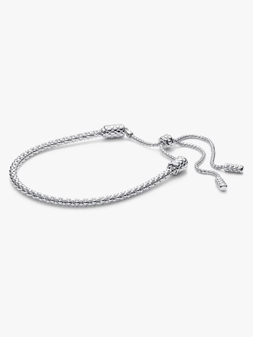 Bracelet en argent à texture cloutée sur fond blanc, vue de profil.