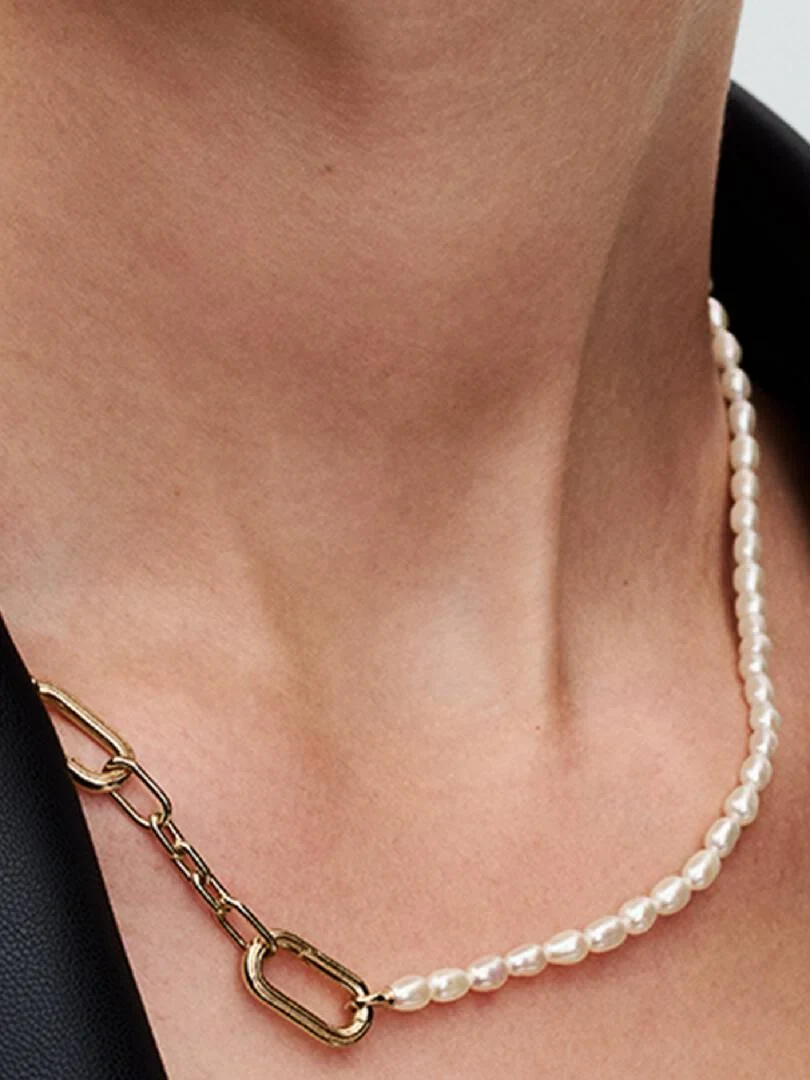 Close-up of the pearl and gold link necklace on a neck, side view with dark background.