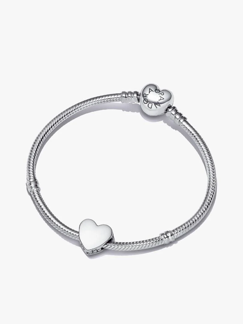 Pulsera de plata vista desde arriba en ángulo inclinado, sobre fondo blanco, mostrando el cierre y charm de corazón.