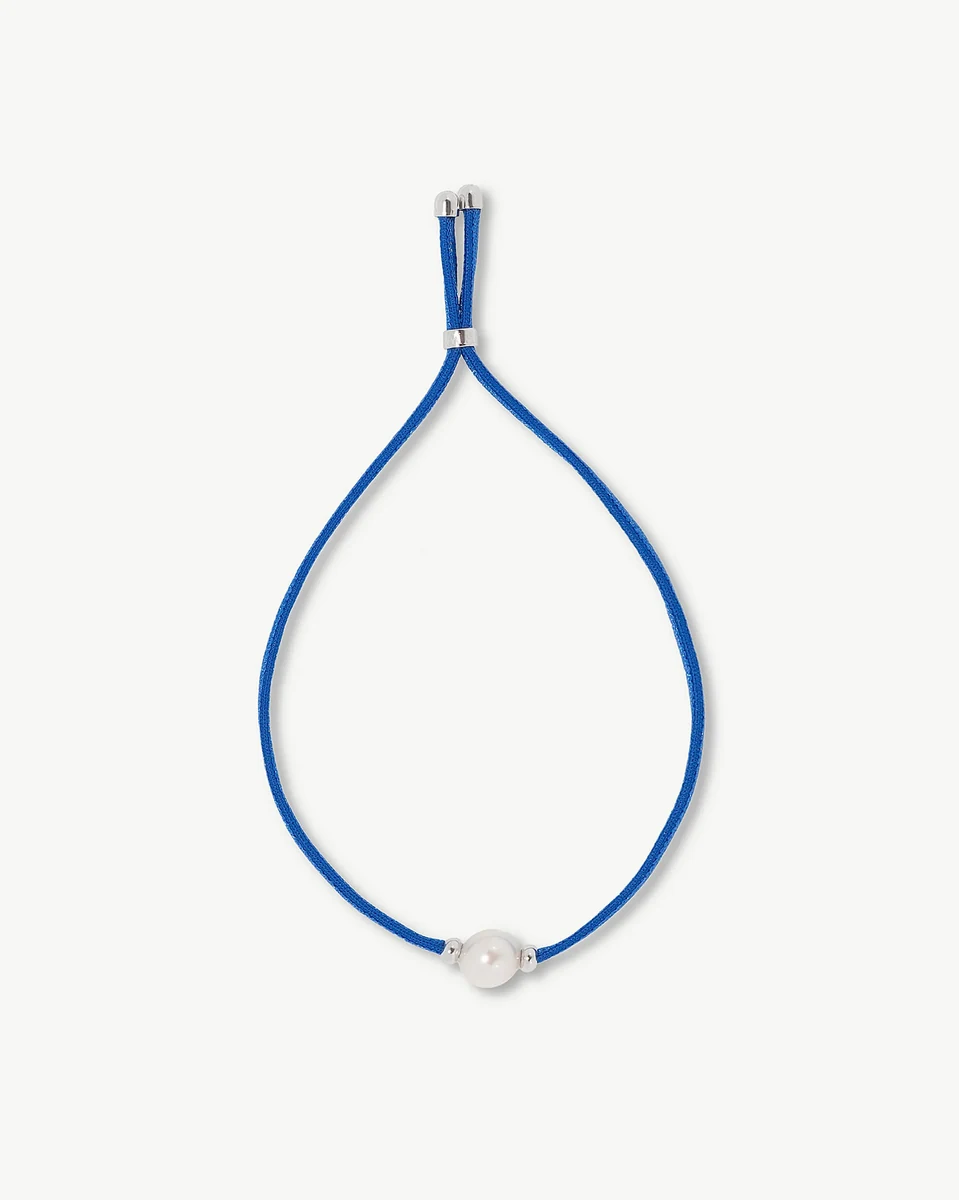 Top view of blue bracelet with white pearl, arranged in a circle on a white background.