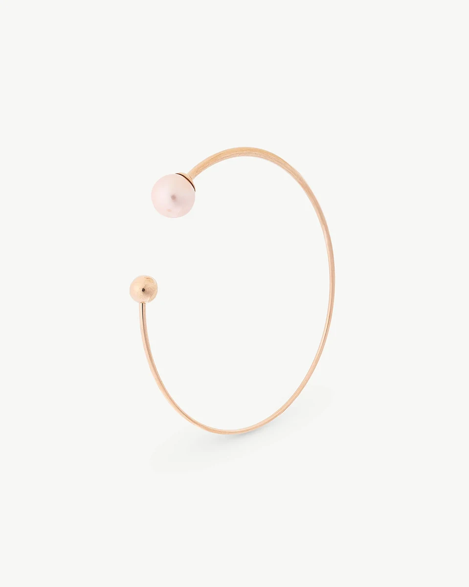 Bracelet jonc en acier rose avec perle, vue de profil sur fond blanc.