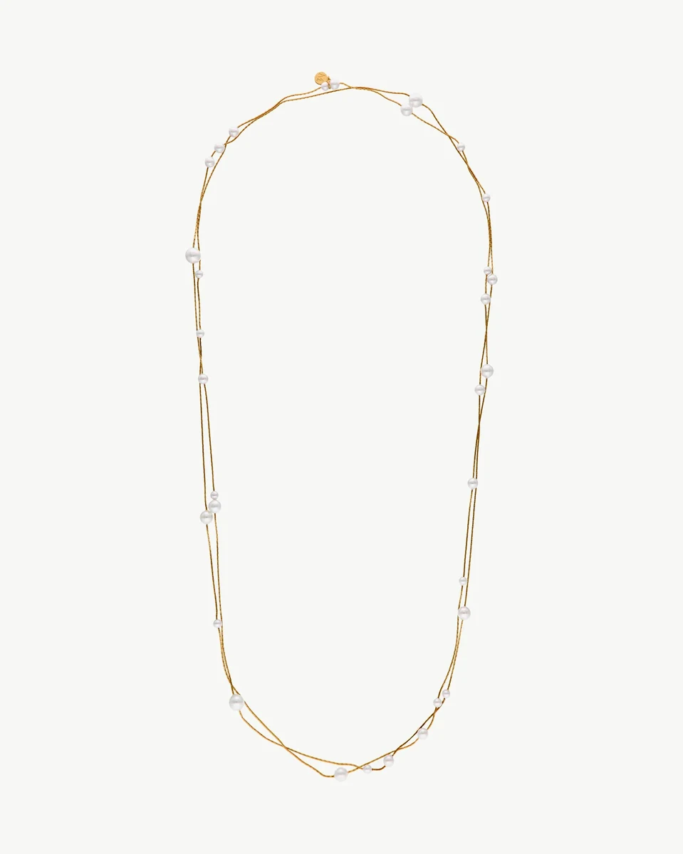 Long pearl and gold chain necklace arranged in a U-shape on a white background.