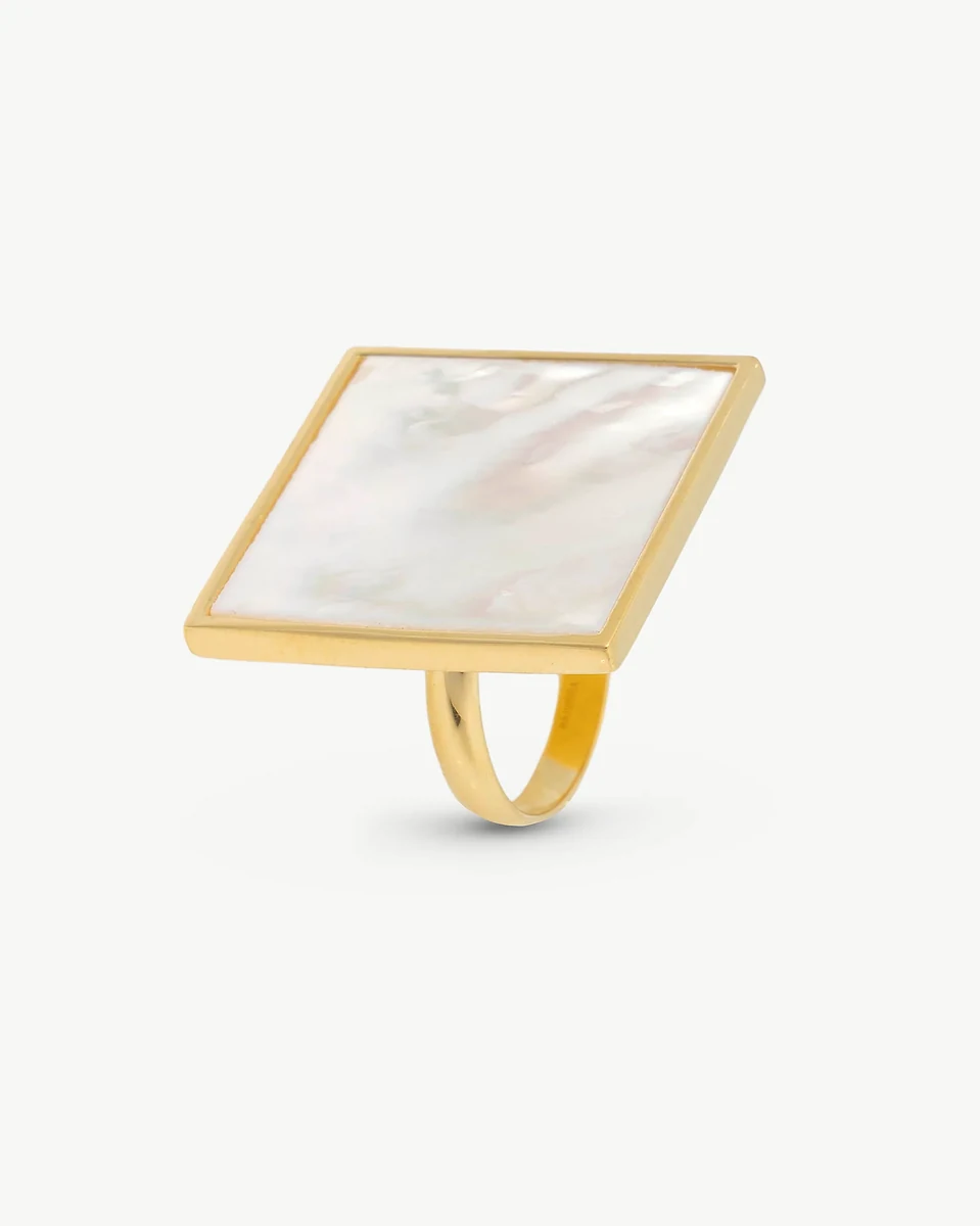 Anillo con pastilla cuadrada de nácar visto en ángulo lateral, sobre fondo blanco puro.