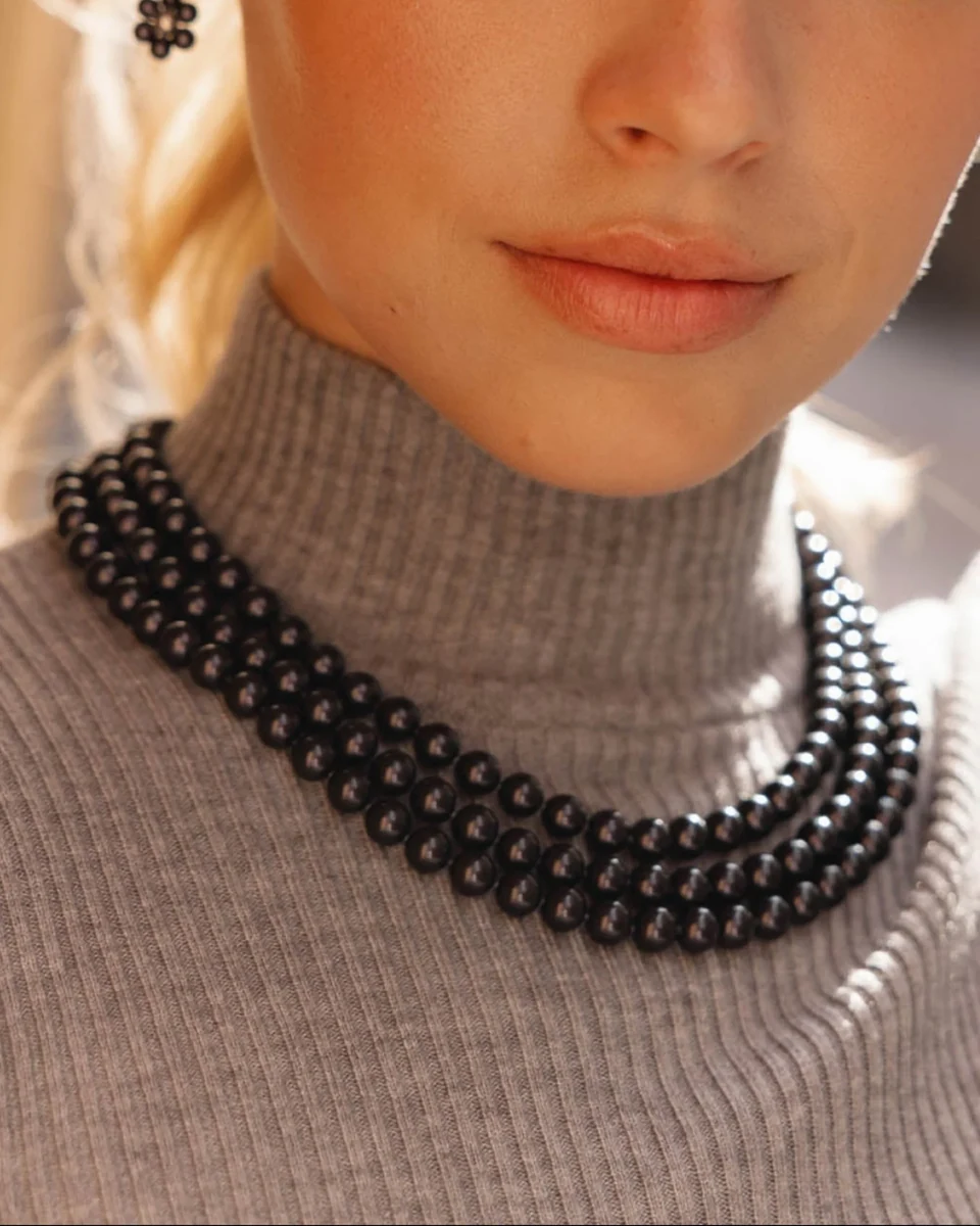 Gros plan d'un collier à trois rangs sur un col roulé gris, vue de face de la mannequin.