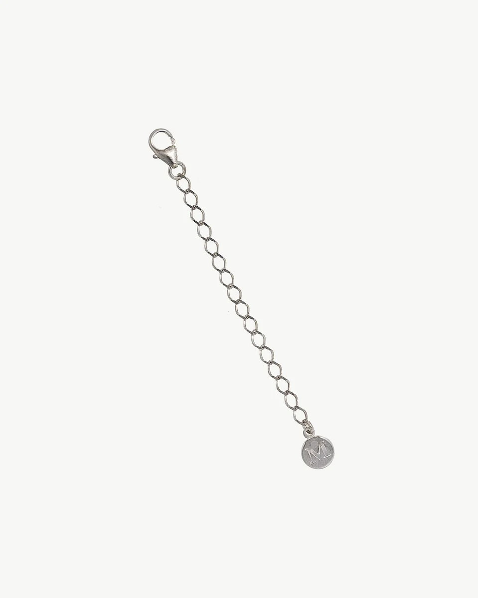 Silver extender chain arranged diagonally on a white background, showing the clasp and the letter M charm.