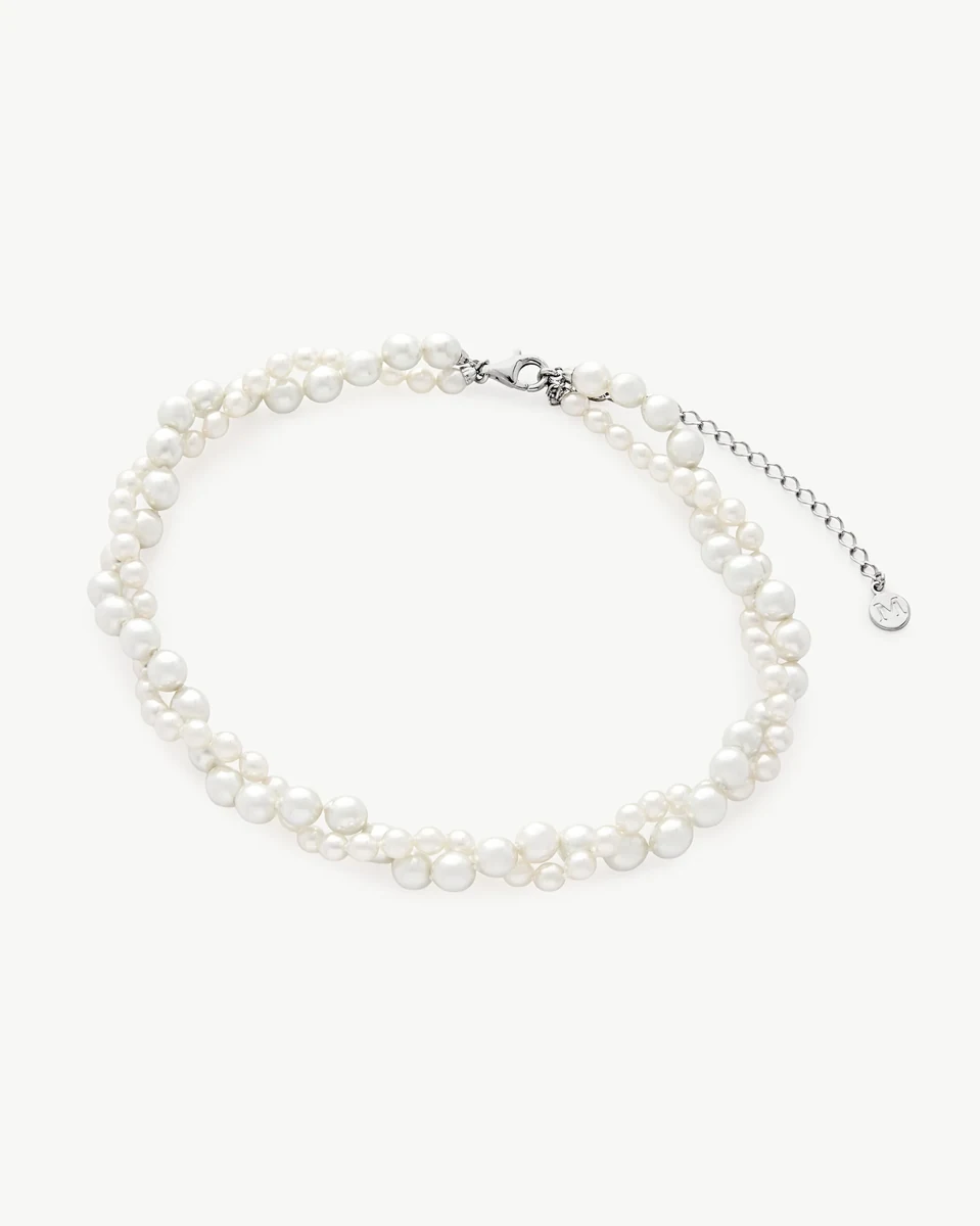 Dubbele streng witte parelketting op een witte achtergrond, bovenaanzicht met de sluiting zichtbaar.