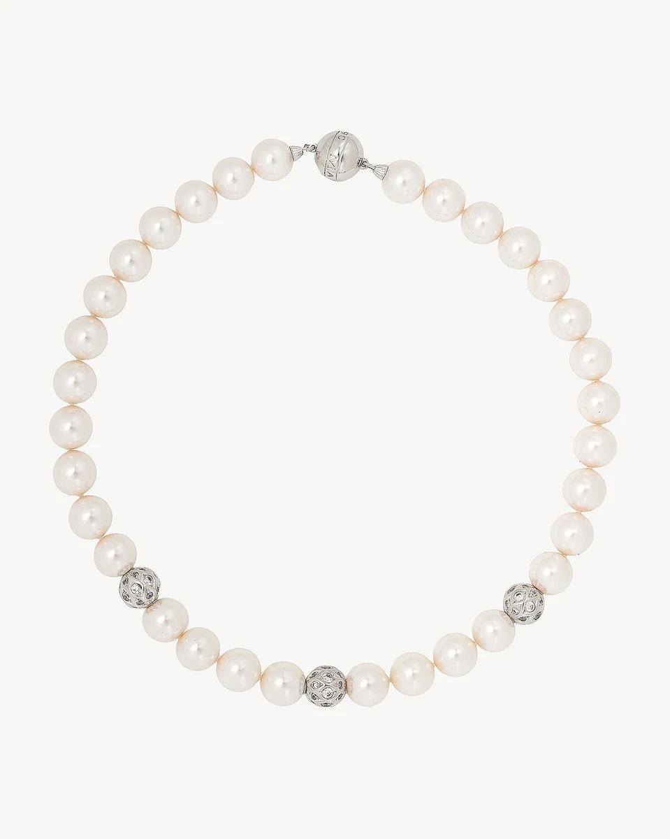 Pearl necklace arranged in a circle on a white background, top view showing silver sphere details.