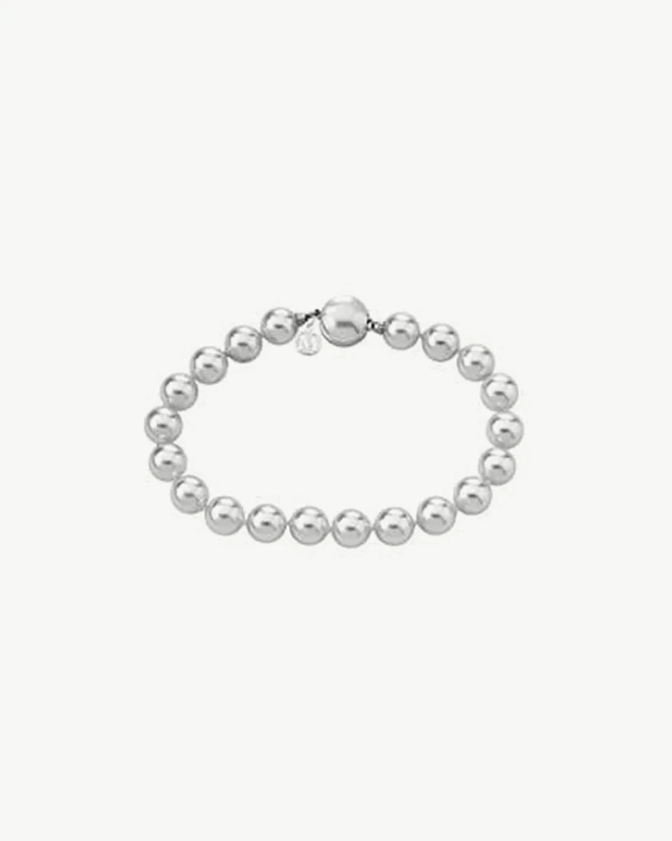 Bracelet en perles blanches disposé en cercle sur fond blanc, vue de dessus.