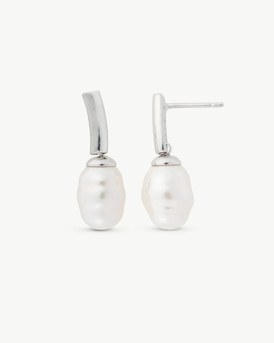 Pareja de pendientes de perla barroca con cierre de espiga en plata, vista frontal sobre fondo blanco.