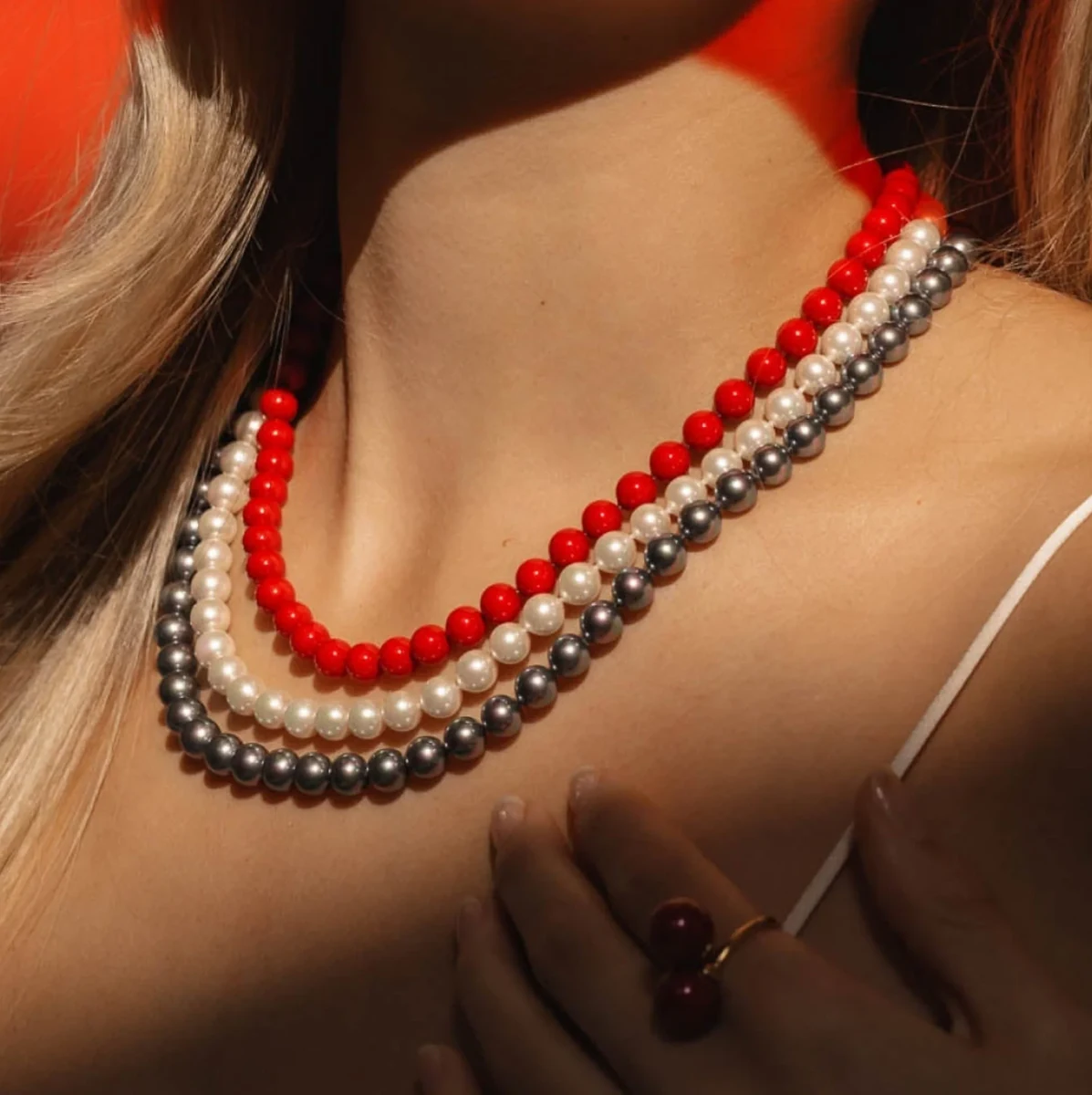 Gros plan du collier à trois rangs sur le cou d'un modèle, vue de profil avec éclairage chaud.