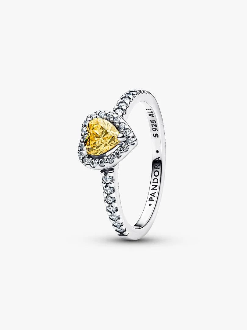 Yellow heart ring shown from a side angle, white background, detail of the setting and pavé band.