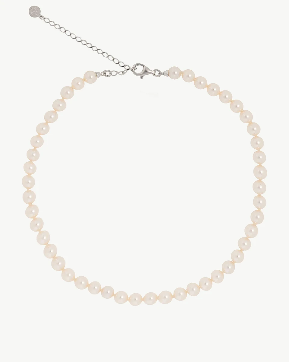 Pearl necklace arranged in a circle on a white background, front view showing clasp and extender chain.