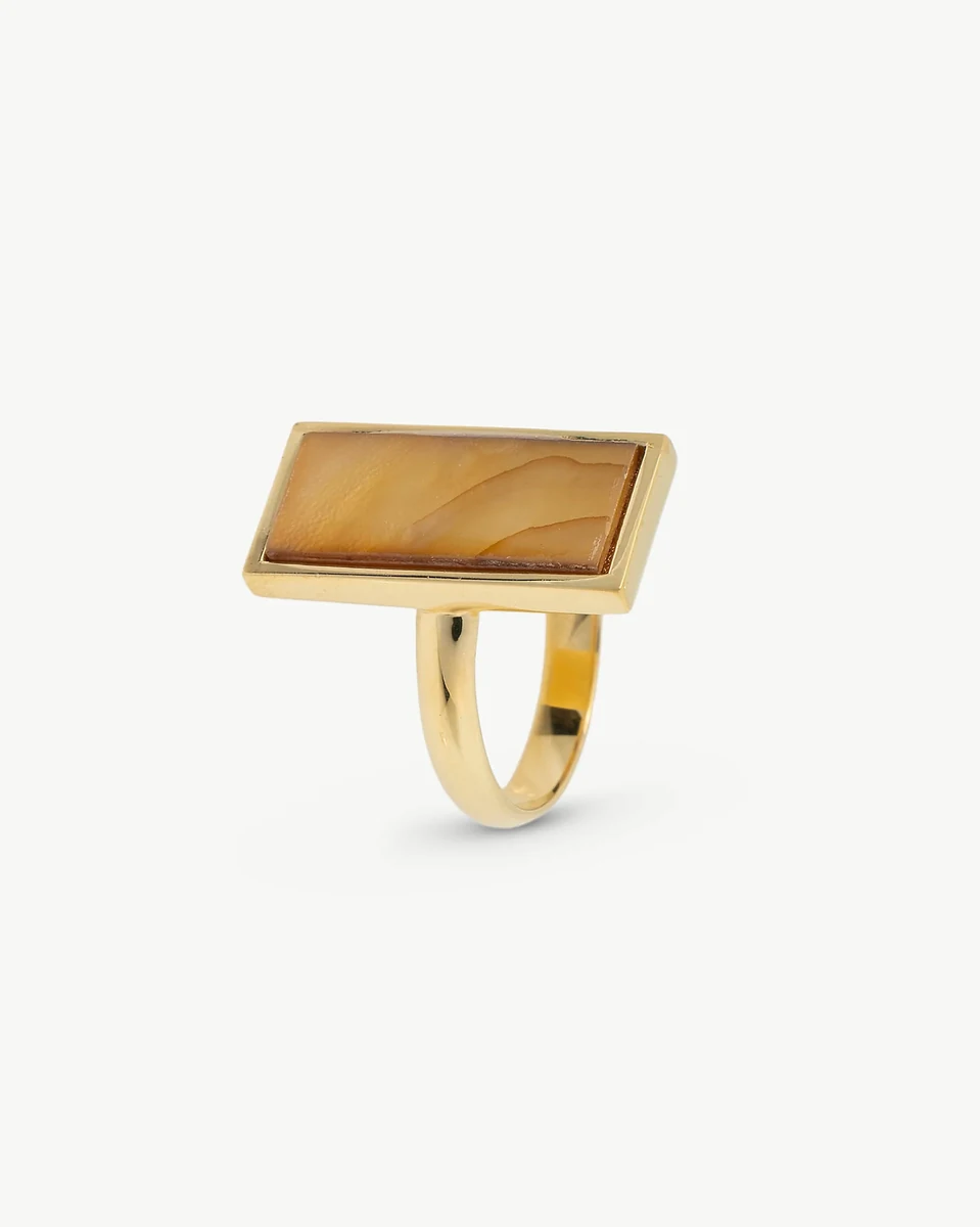 Anillo con pastilla rectangular de nácar marrón, vista lateral en ángulo, fondo blanco neutro.