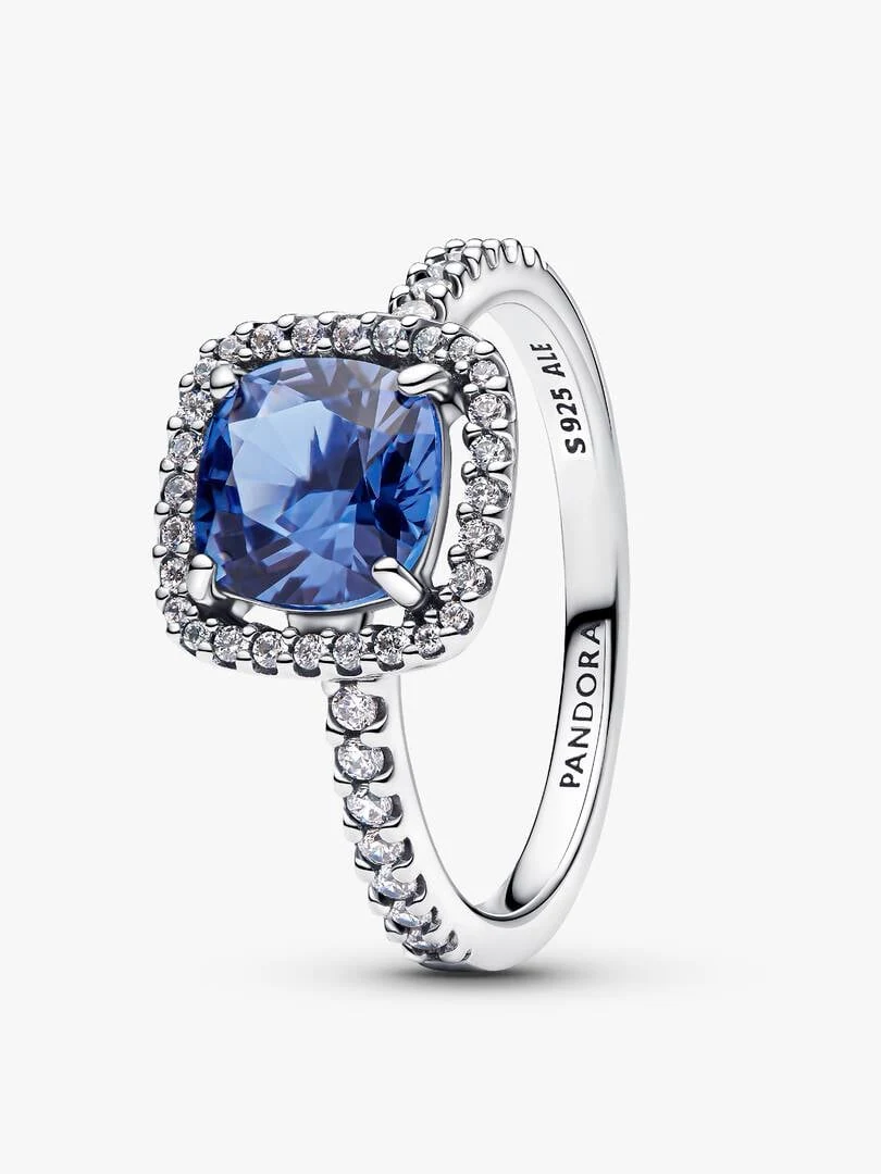 Silberner Ring mit blauem Mittelstein und Halo, seitliche Ansicht im Winkel auf weißem Hintergrund.