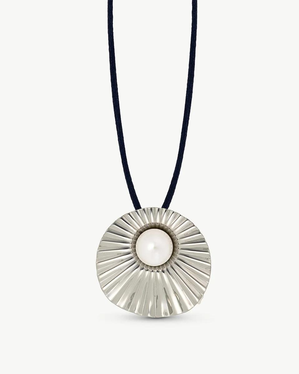 Vue de face d'un pendentif perle dans un serti circulaire strié sur cordon bleu, fond blanc.