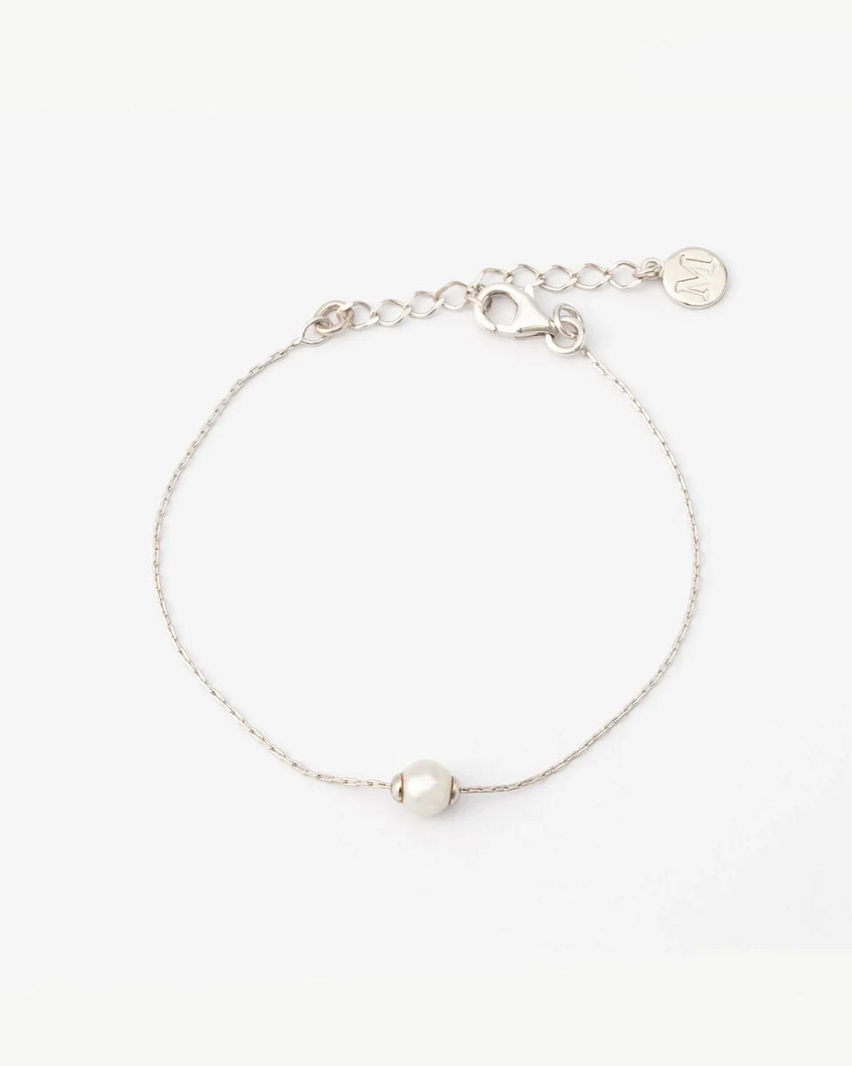 Fine chain bracelet with white pearl, front view on white background, showing clasp and circular charm.