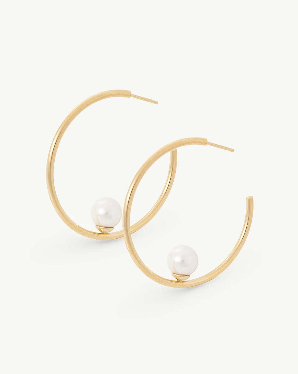 Pair of gold hoop earrings with white pearl, front angle view on a white background.
