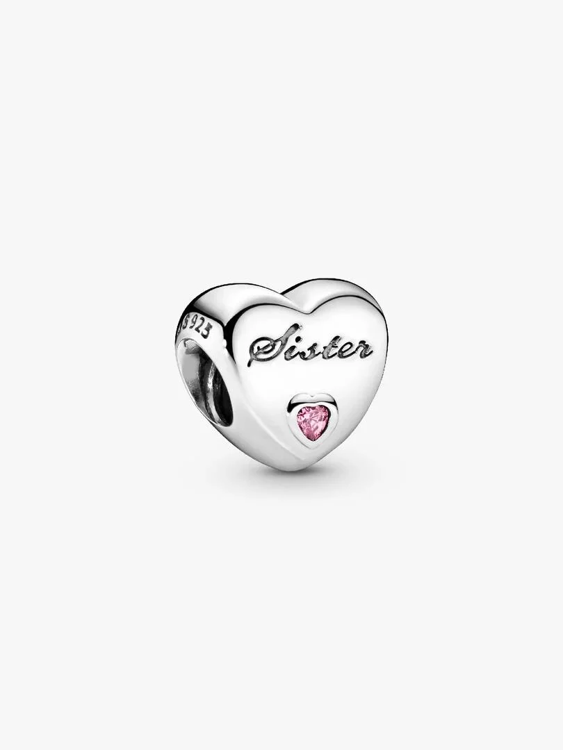 Charm de corazón en plata con la palabra 'Sister' grabada y una circonita rosa, vista frontal sobre fondo blanco.
