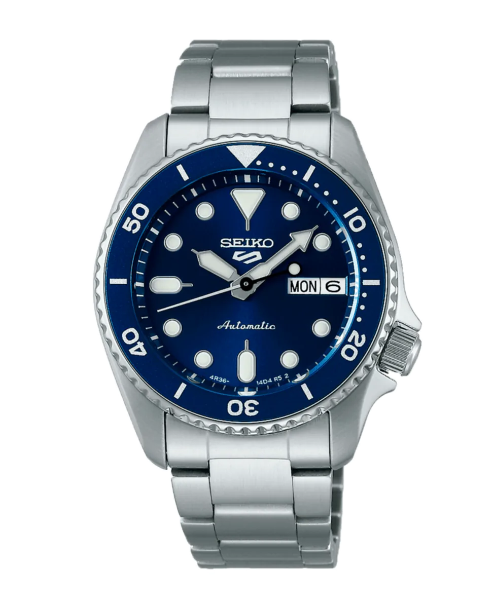 Vista frontal del reloj con esfera azul y brazalete de acero, centrado sobre fondo blanco.