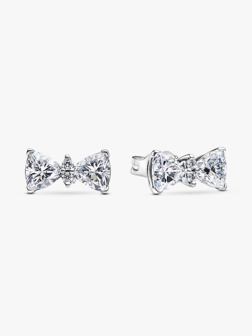 Pair of bow stud earrings in silver with cubic zirconia, front and side view on white background.
