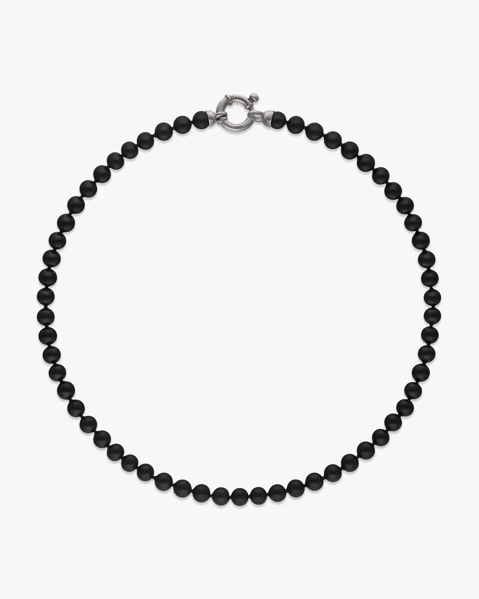 Black pearl necklace arranged in a circle on a white background, front view with silver clasp visible.