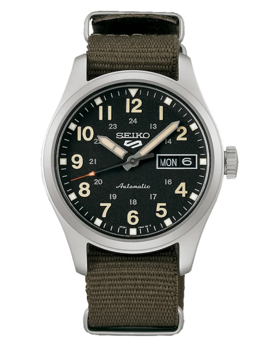 Vista frontal del reloj con esfera negra y correa de nylon verde caqui, fondo blanco.