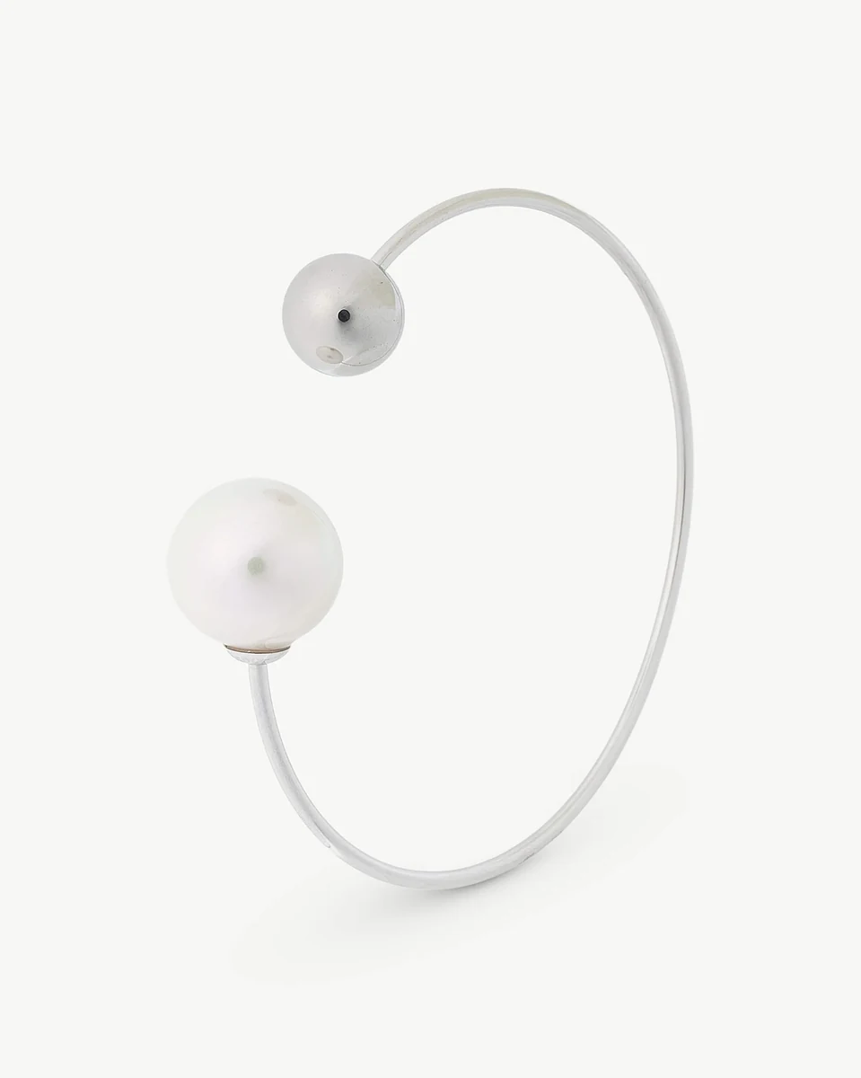 Bracelet en acier vu de profil sur fond blanc, mettant en valeur la perle et la boule d'acier.