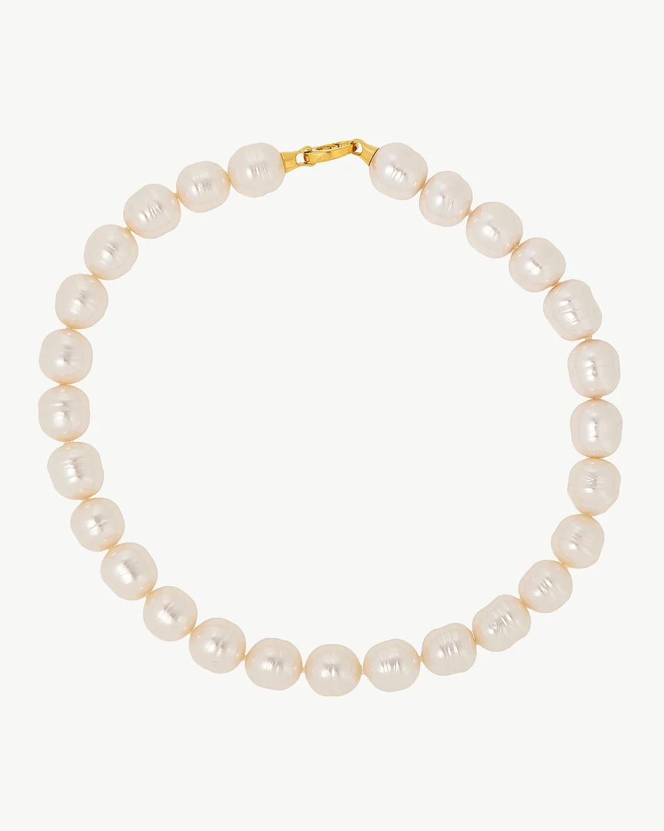 Collier de perles blanches disposé en cercle sur fond blanc, vue de face avec fermoir doré visible.