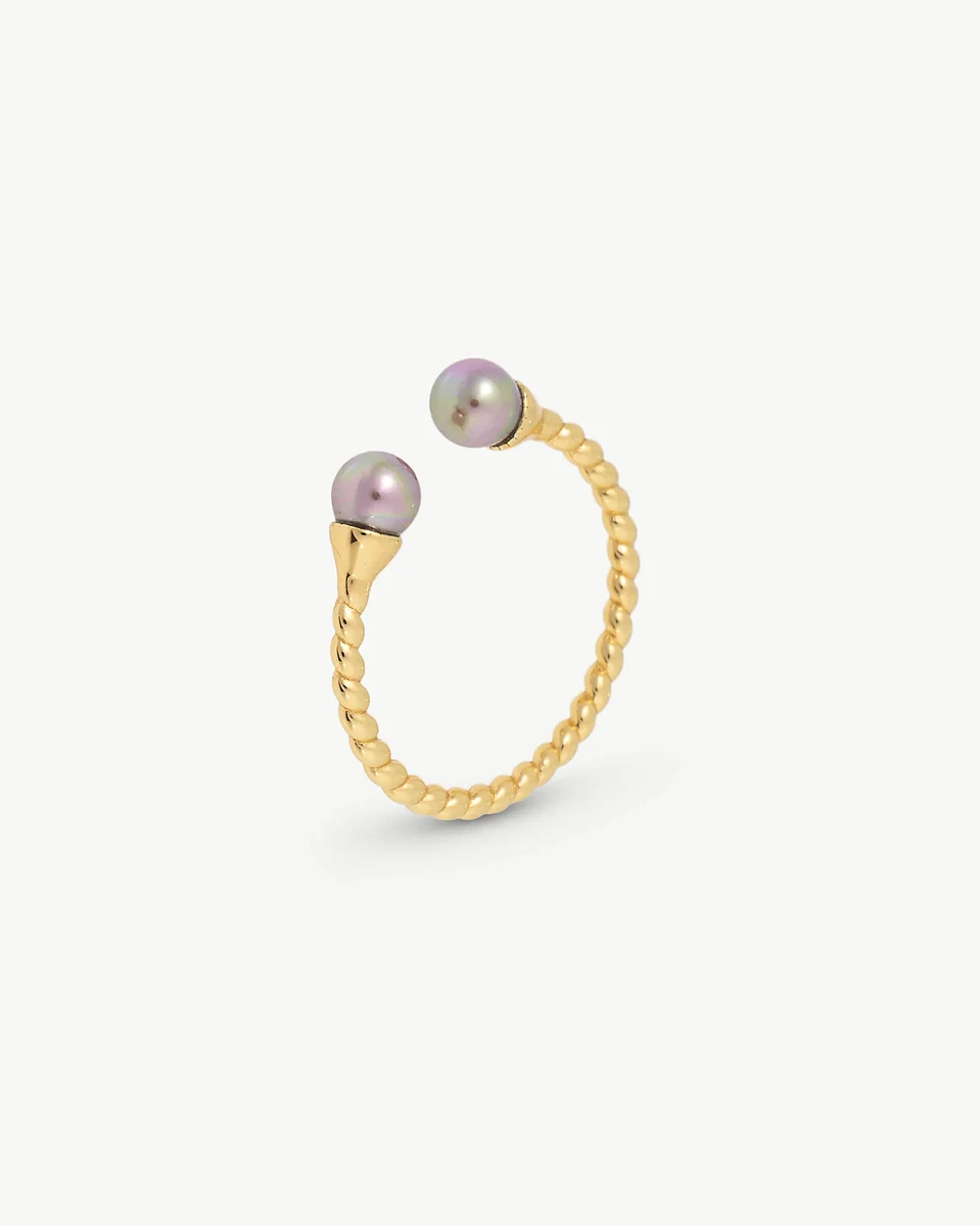 Anillo de diseño trenzado con dos perlas aubergine, vista lateral en ángulo sobre fondo blanco.
