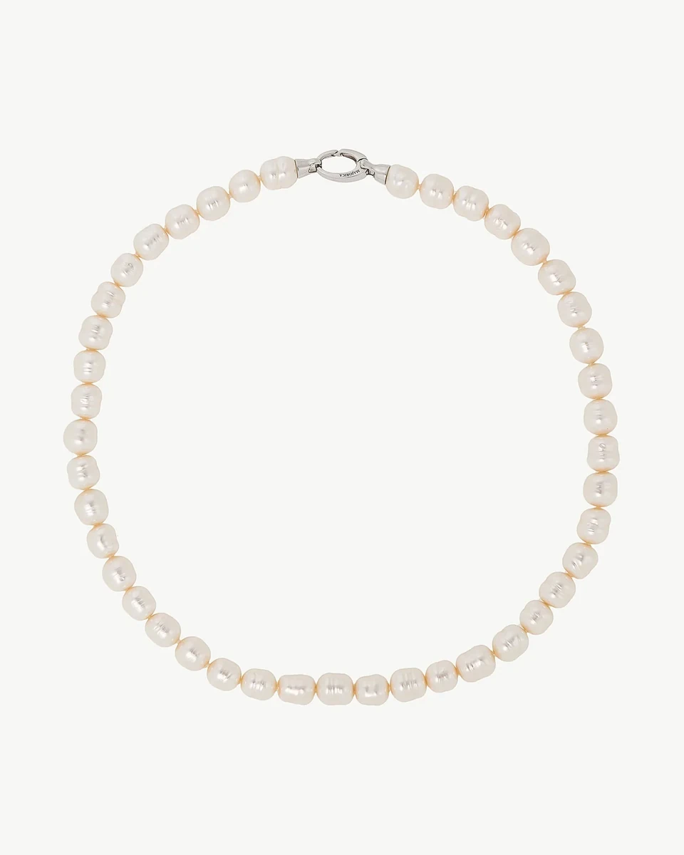 Collar de perlas barrocas blancas dispuesto en círculo sobre fondo blanco, vista cenital con cierre visible.