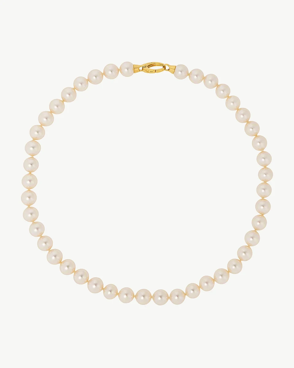 Pearl necklace arranged in a circle on a white background, front view with gold clasp visible.