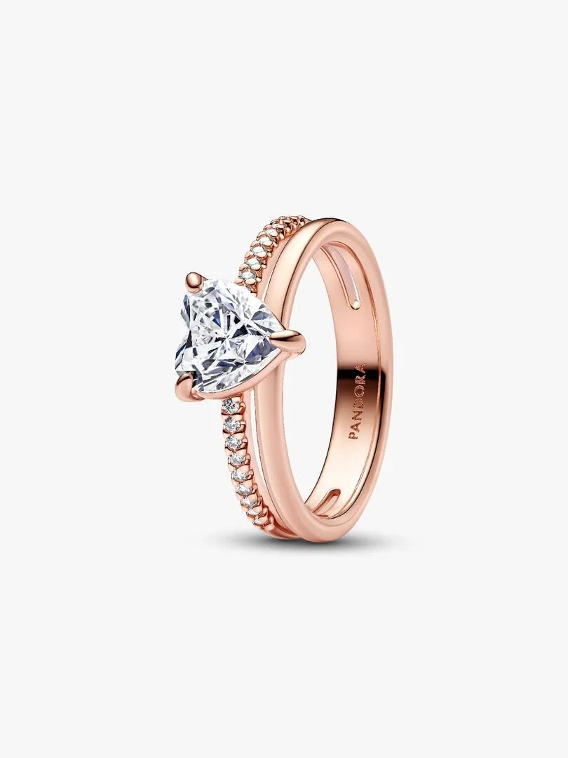 Anillo de doble banda con corazón central, vista lateral en ángulo, fondo blanco neutro.