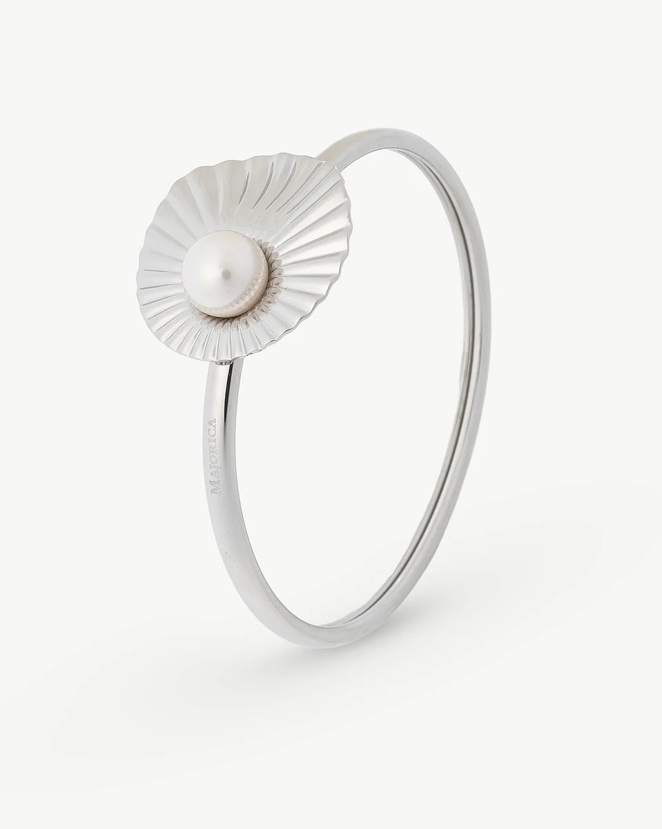 Bracelet jonc en acier avec une perle centrale au design radial, vue de profil sur fond blanc.